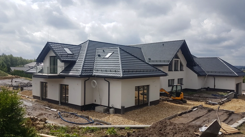 Dwukondygnacyjny dom jednorodzinny z czarnym dachem i białymi ścianami w stanie surowym zamkniętym