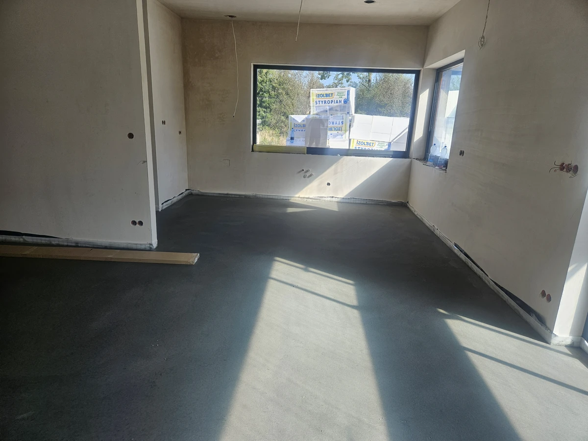 Wylewki betonowe w dużym pomieszczeniu w stanie deweloperskim, świeżo wyrównana posadzka przed pracami wykończeniowymi