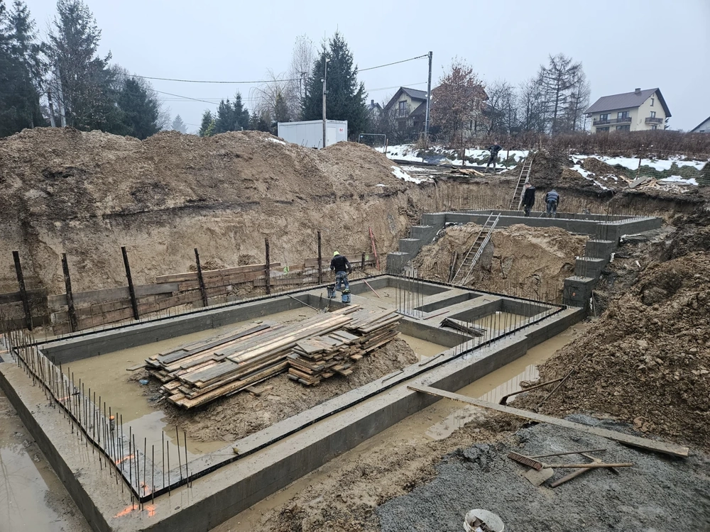 Fundamenty domu jednorodzinnego z widocznym zbrojeniem i świeżym betonem