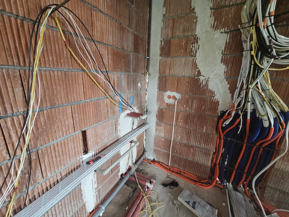 Instalacje elektryczne – kable i przewody na surowej ceglanej ścianie budowy domu