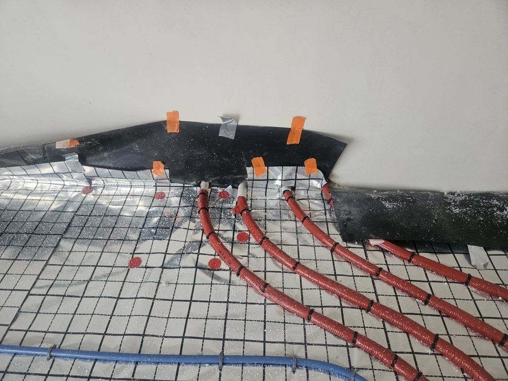 Rurki instalacji hydraulicznej ogrzewania podłogowego ułożone na siatce i izolacji przed wylewką posadzki