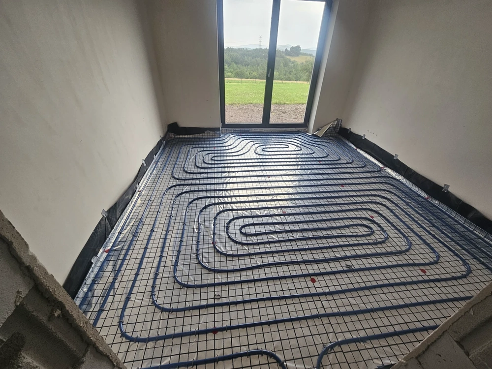 Instalacje hydrauliczne: rury ogrzewania podłogowego rozłożone na siatce przed wylewką