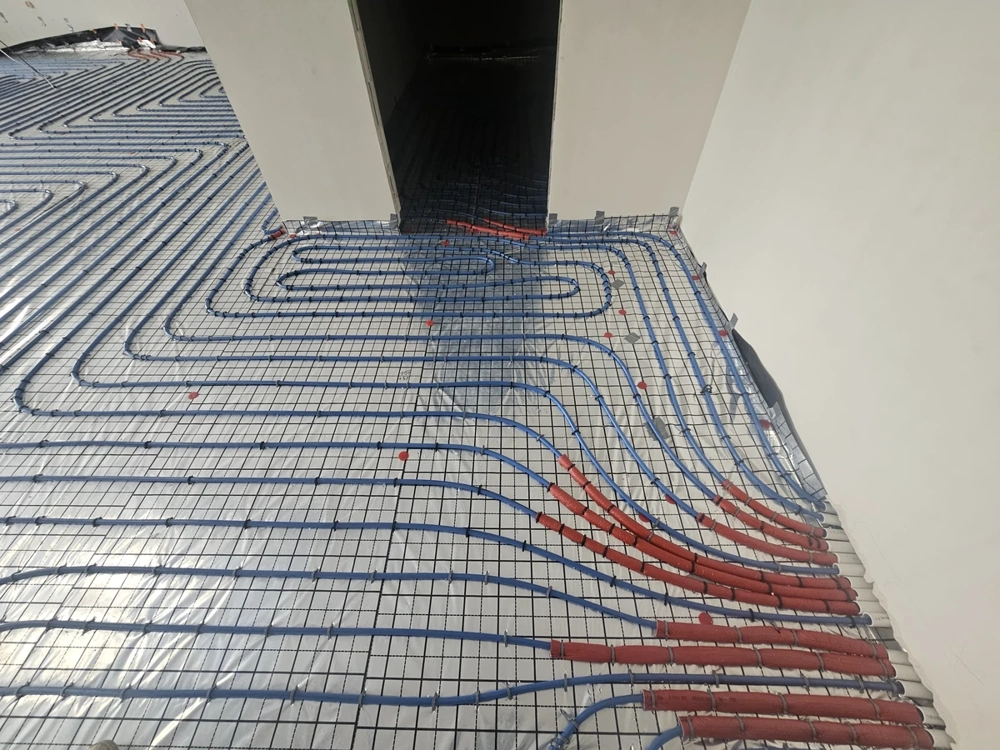 Instalacje hydrauliczne rur ogrzewania podłogowego ułożone na folii izolacyjnej i siatce zbrojeniowej