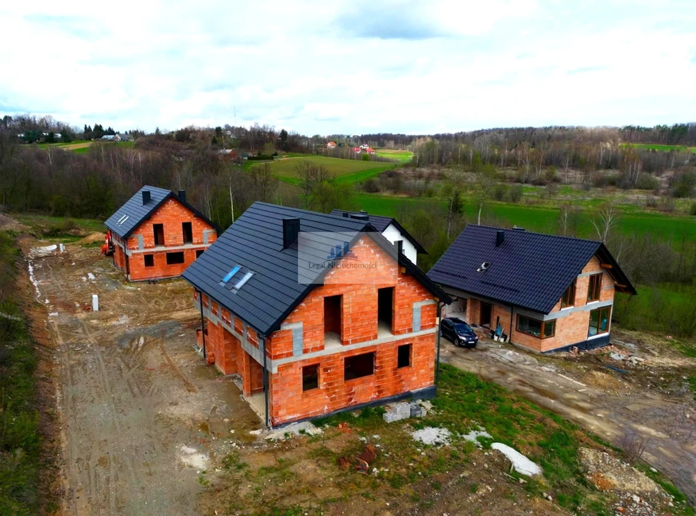 Trzy domy jednorodzinne w fazie Stan surowy otwarty z murowanymi ścianami i dachami na placu budowy